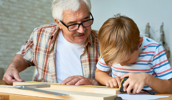 Un enfant mesure une planche sous l’œil d’un senior